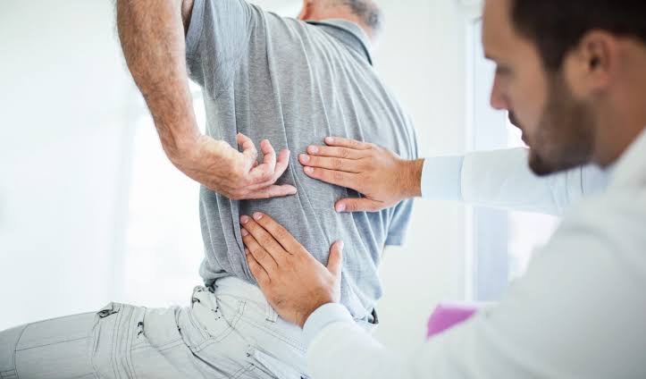 doctor checking patient with lower back pain